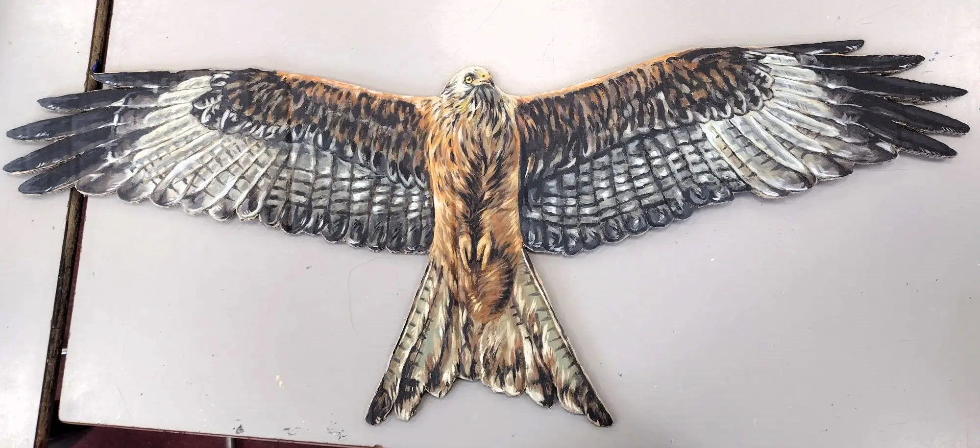 A painting of a red kite with its wings open